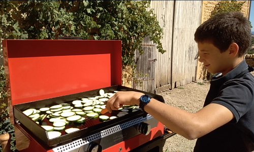 David,12 ans,  cuisine sur une Plancha gaz Rainbow rouge